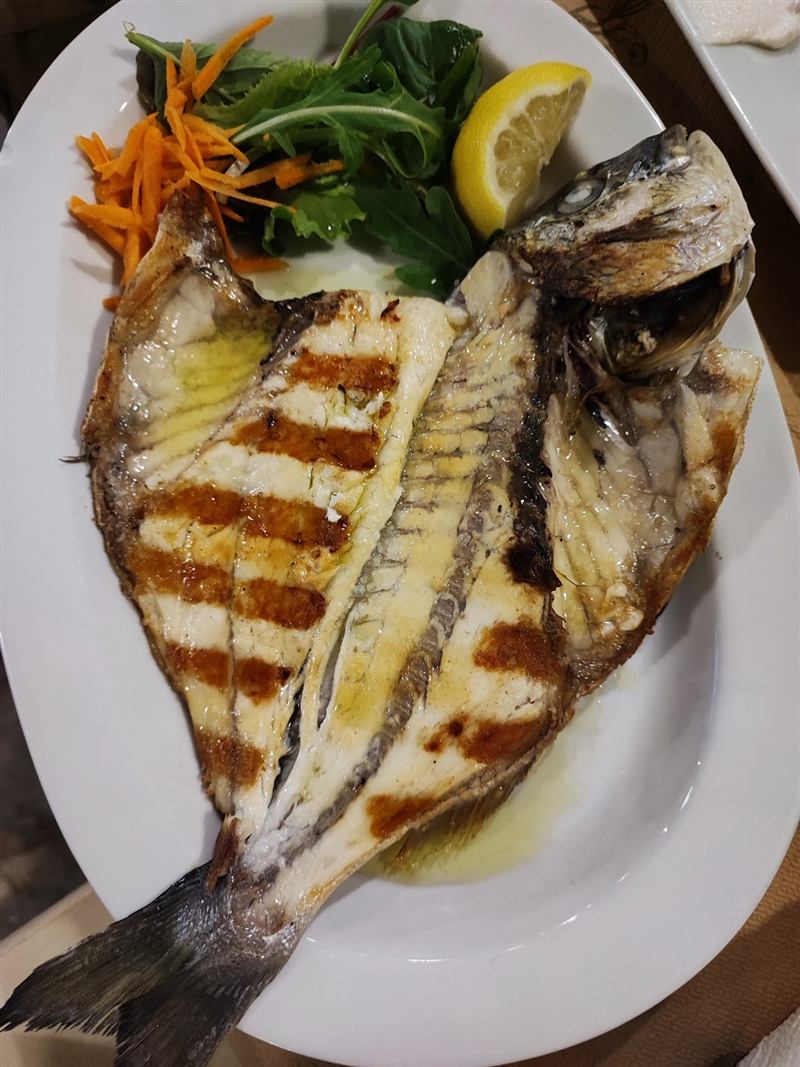 Whole grilled dorada served with lemon and greens
